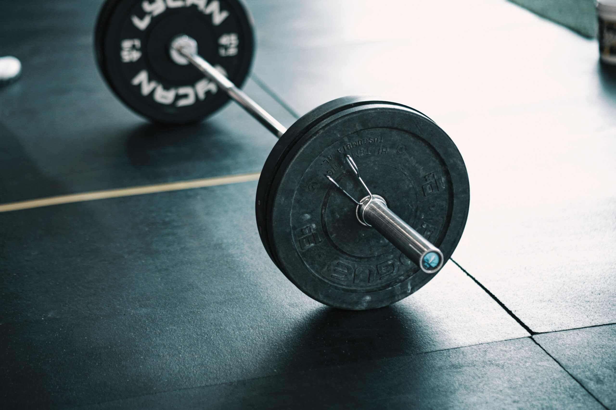 Close up of Olympic barbell plates on gym flooring ready for strength training