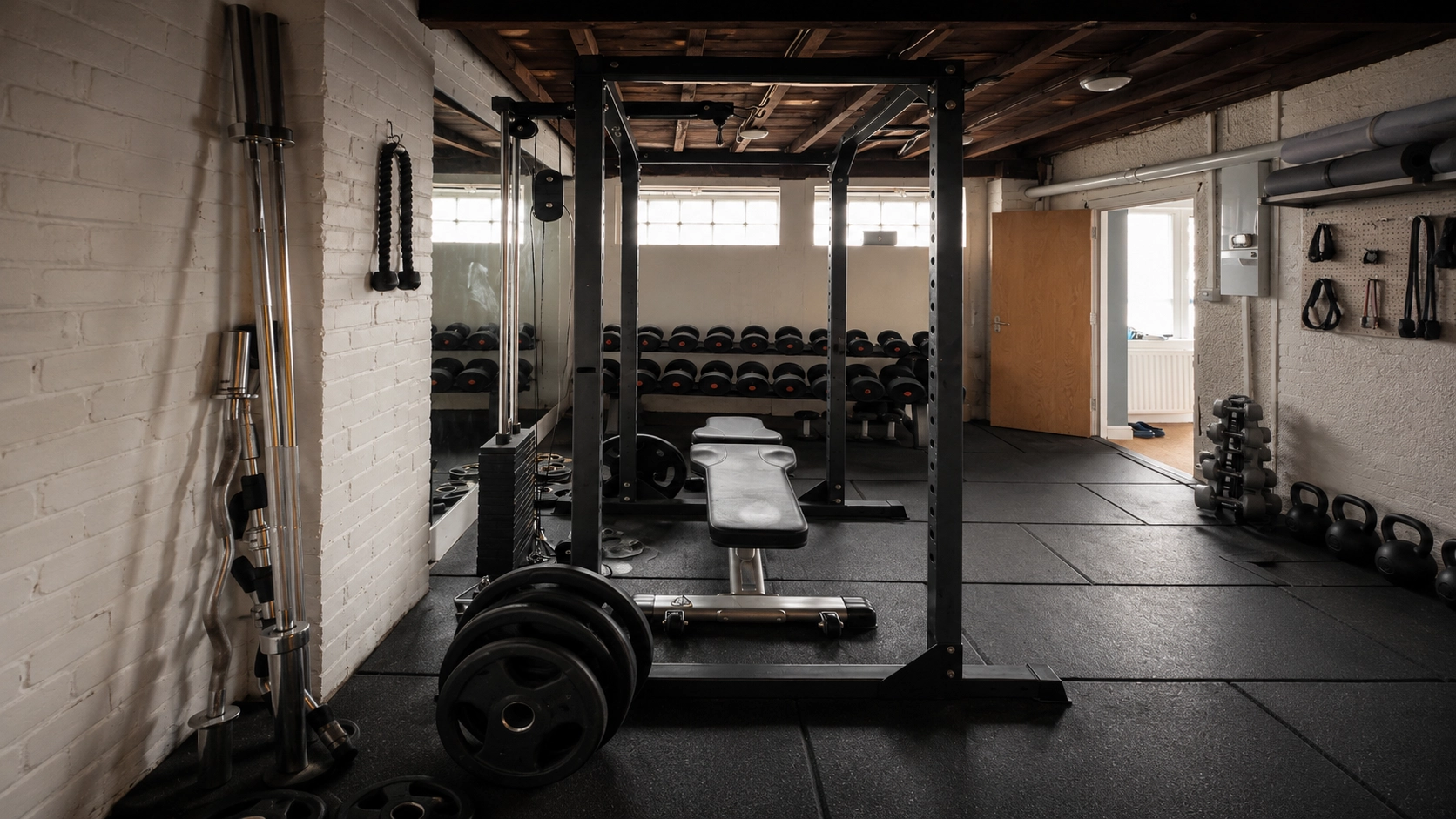 Well-organized home gym with power racks, dumbbells, weight bench, and barbells demonstrating a complete training setup