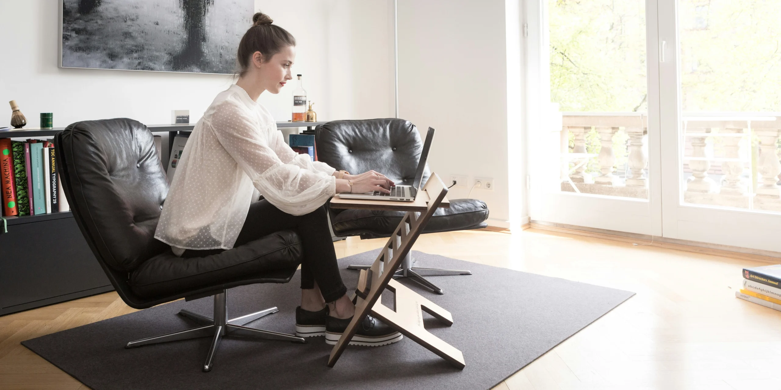 Woman exercising on under desk elliptical while working on laptop in home office
