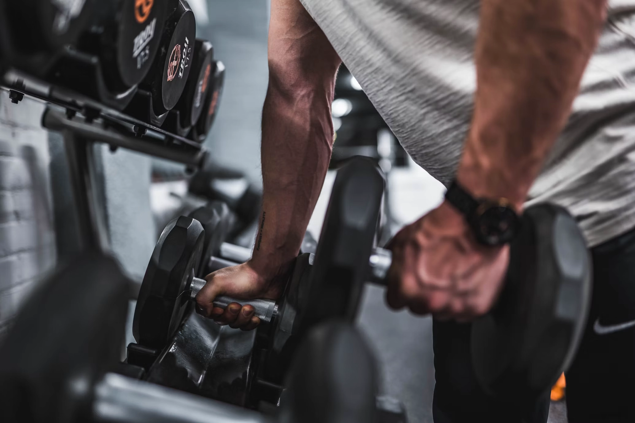 D adjustable Close up of person holding adjustable dumbbell with multiple weights on rack