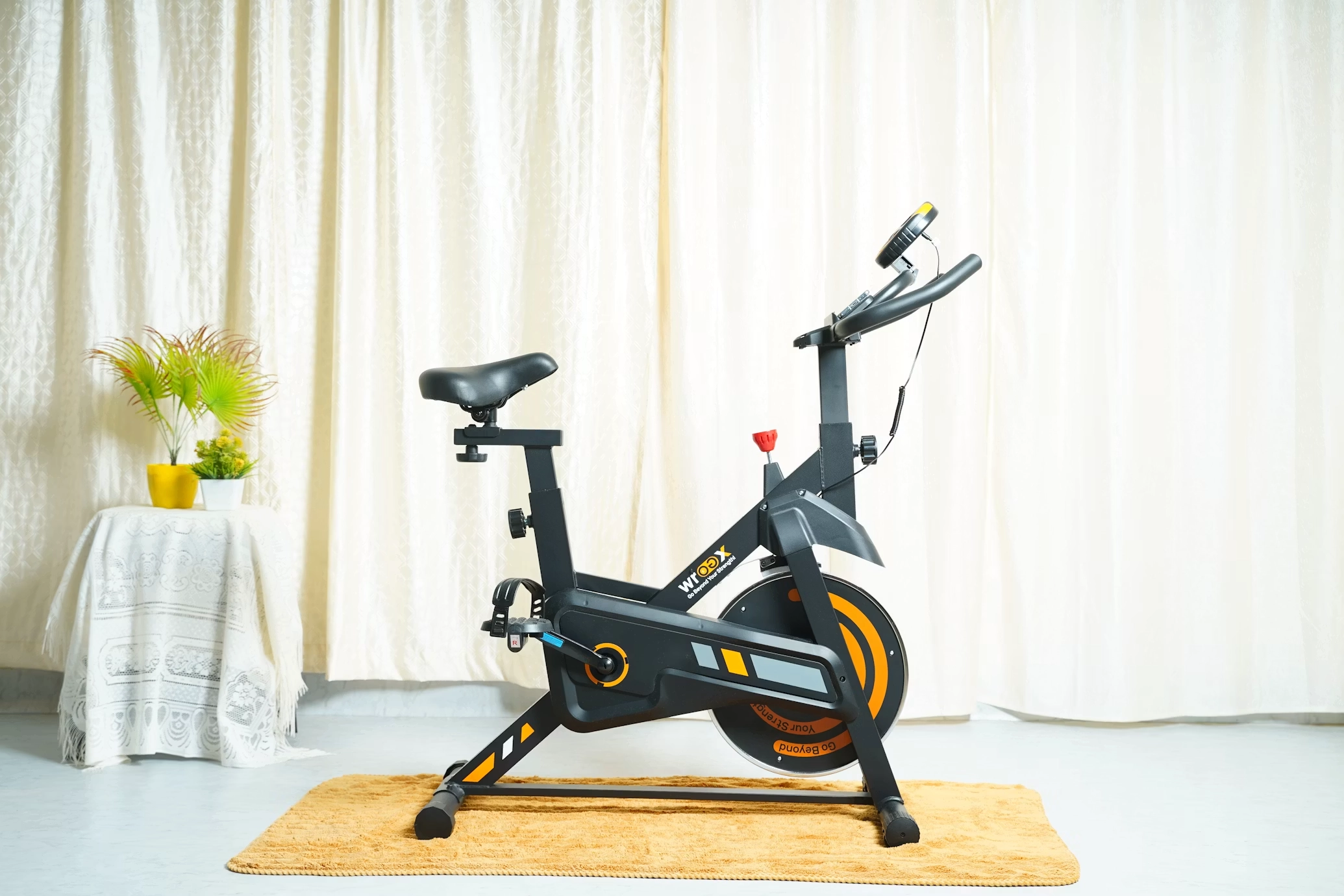 EB Magnetic Resistance Spin Bike Black and orange magnetic resistance spin bike on mat in minimalist gym home studio