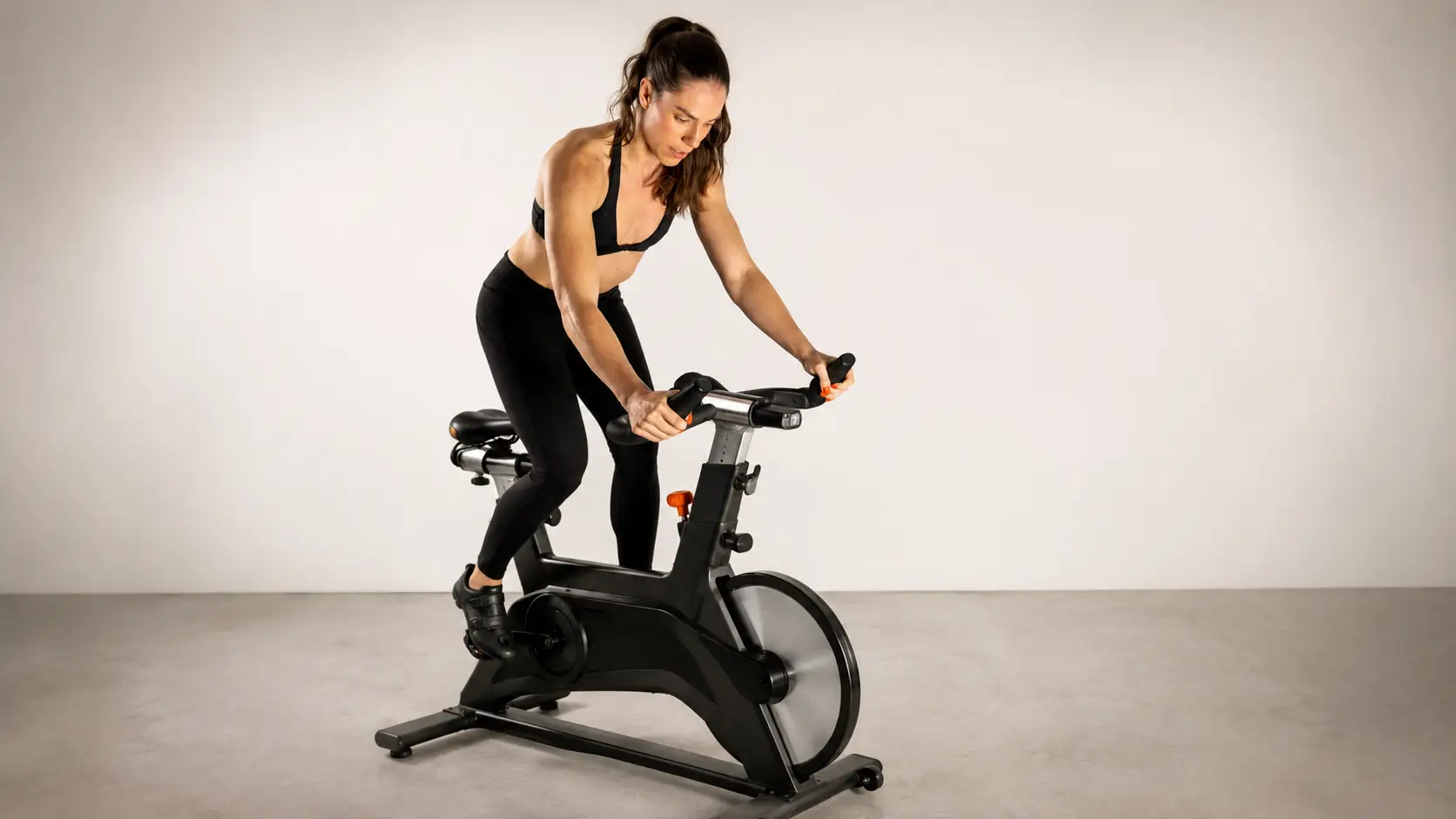 Woman performing high-intensity spin bike workout for cardio fitness training