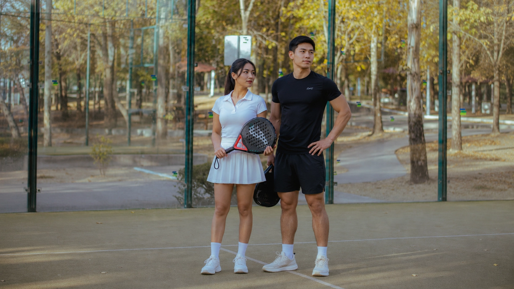 Active couple in casual athletic wear at outdoor tennis court with perforated racket, demonstrating an active lifestyle that requires proper calorie intake planning