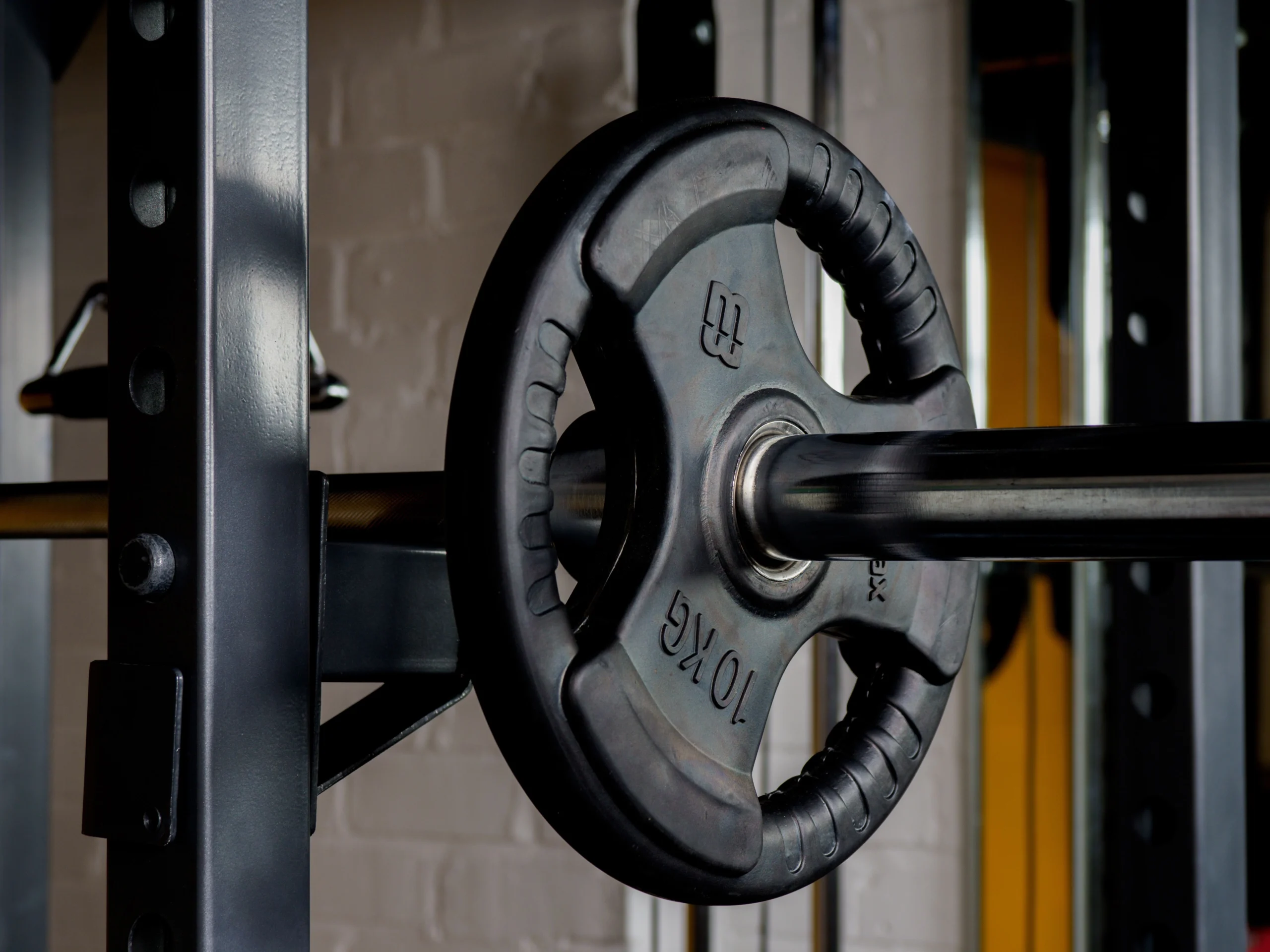 Close-up of a weight plate loaded on a barbell inside a home gym setup