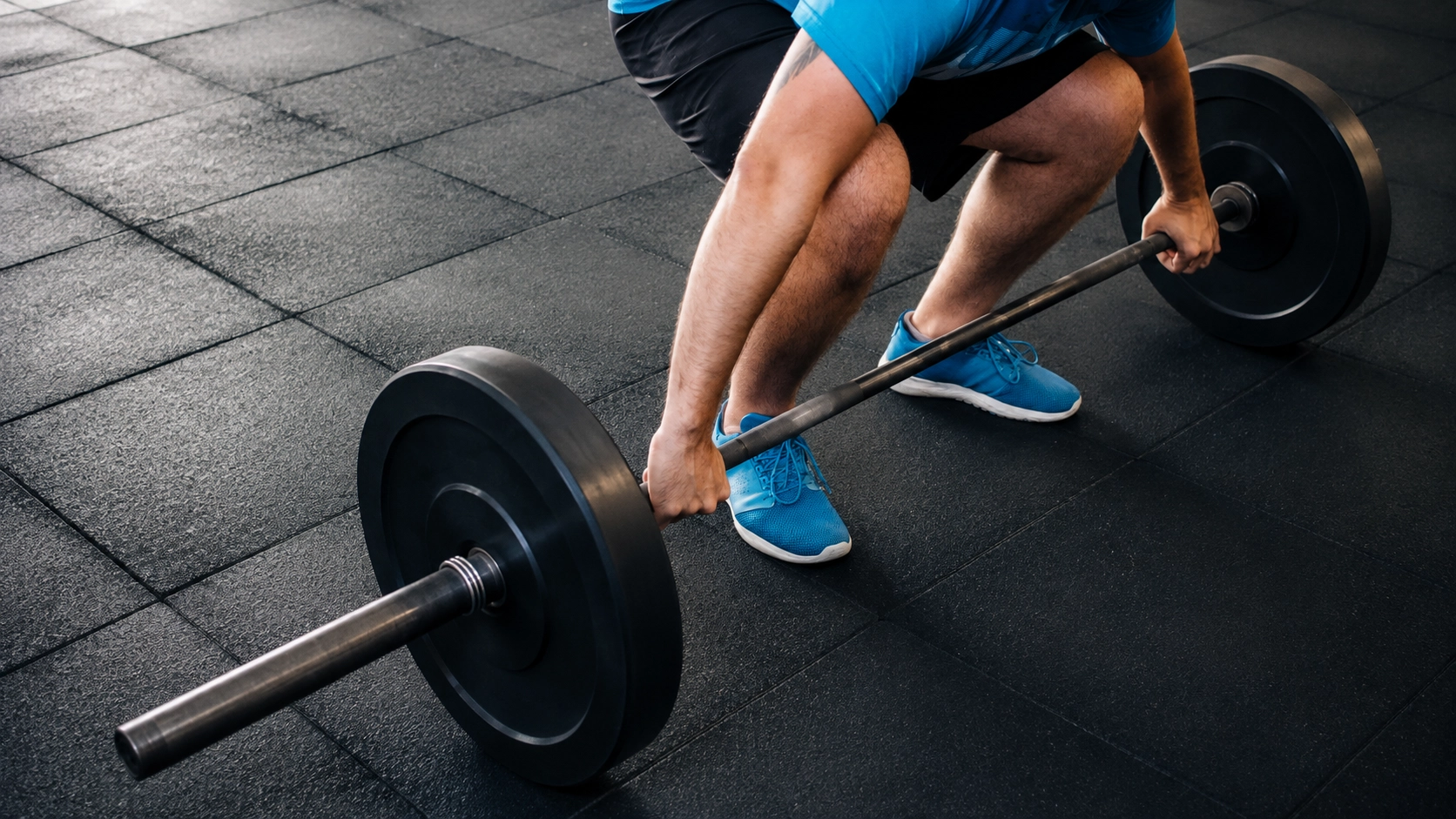 Man performing a deadlift lockout position with a loaded Olympic barbell demonstrating proper lifting form
