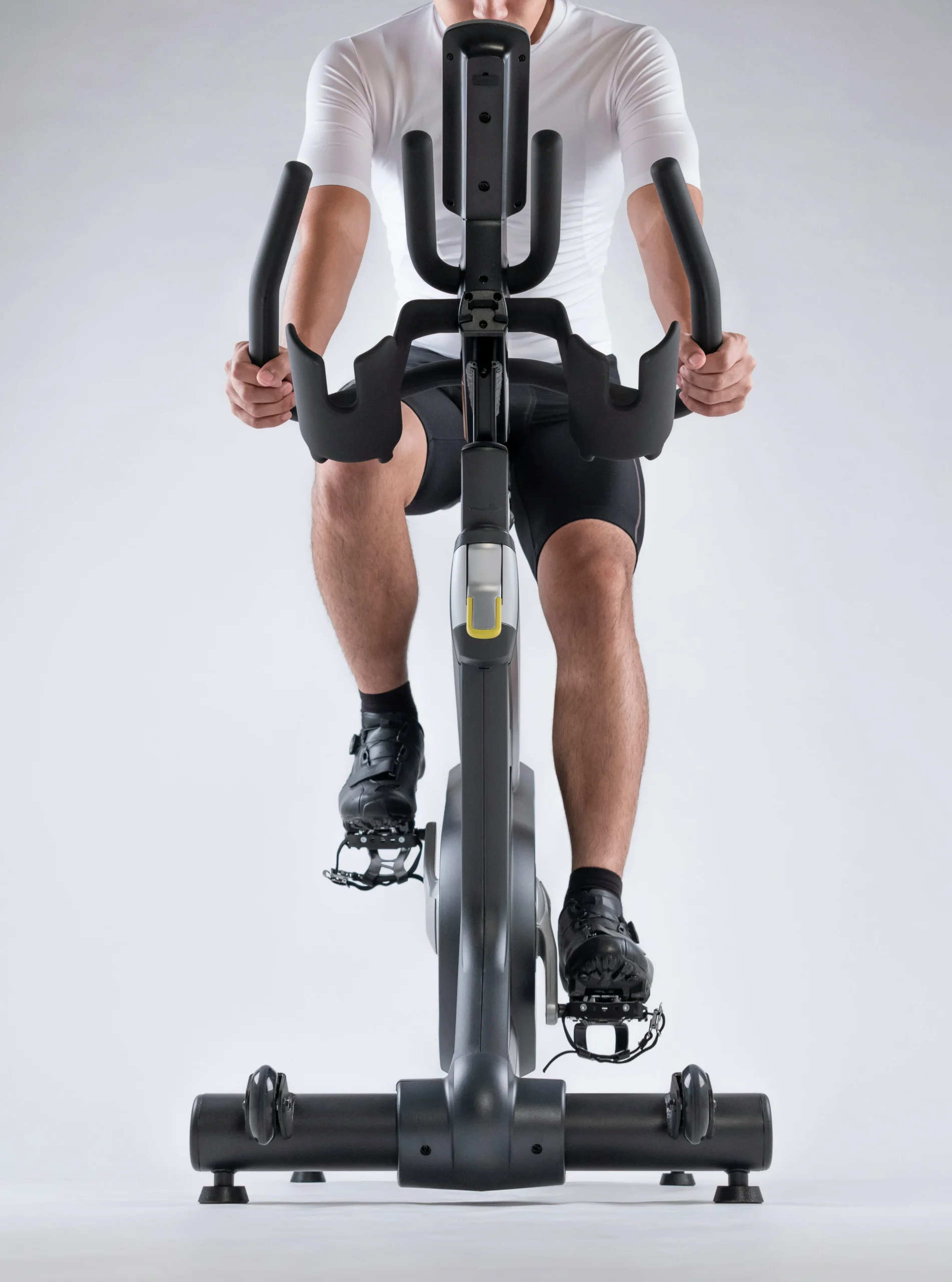 Man in cycling shoes gripping handlebars on stationary exercise bike close up view