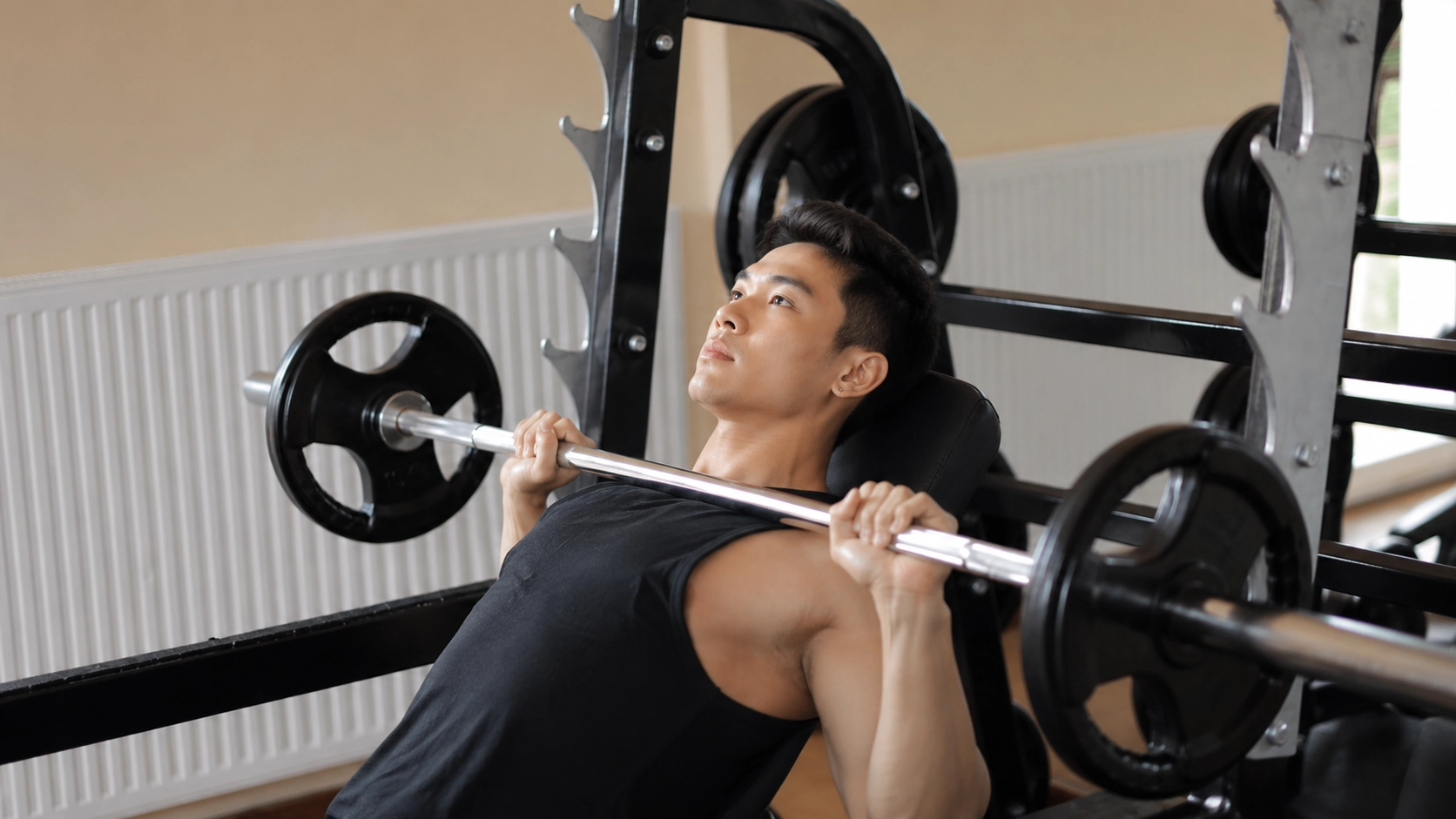Man performing a barbell chest press on a Smith machine in a home gym environment