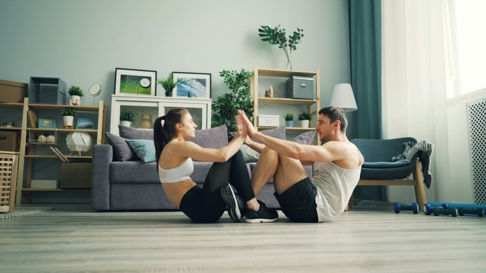 Couple doing a partner sit-up workout on the living room floor