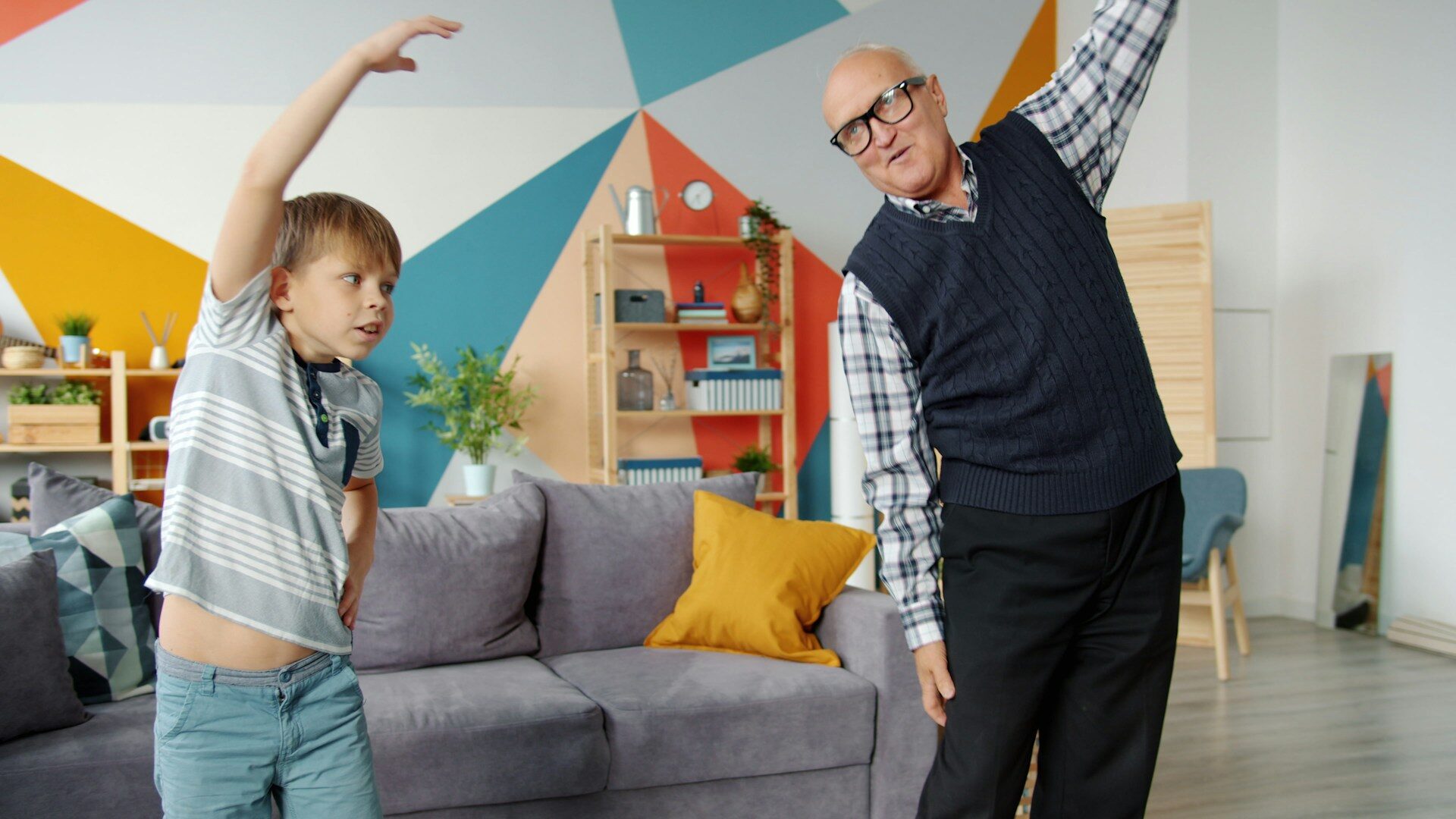 Grandfather and grandson stretching together in a bright living room
