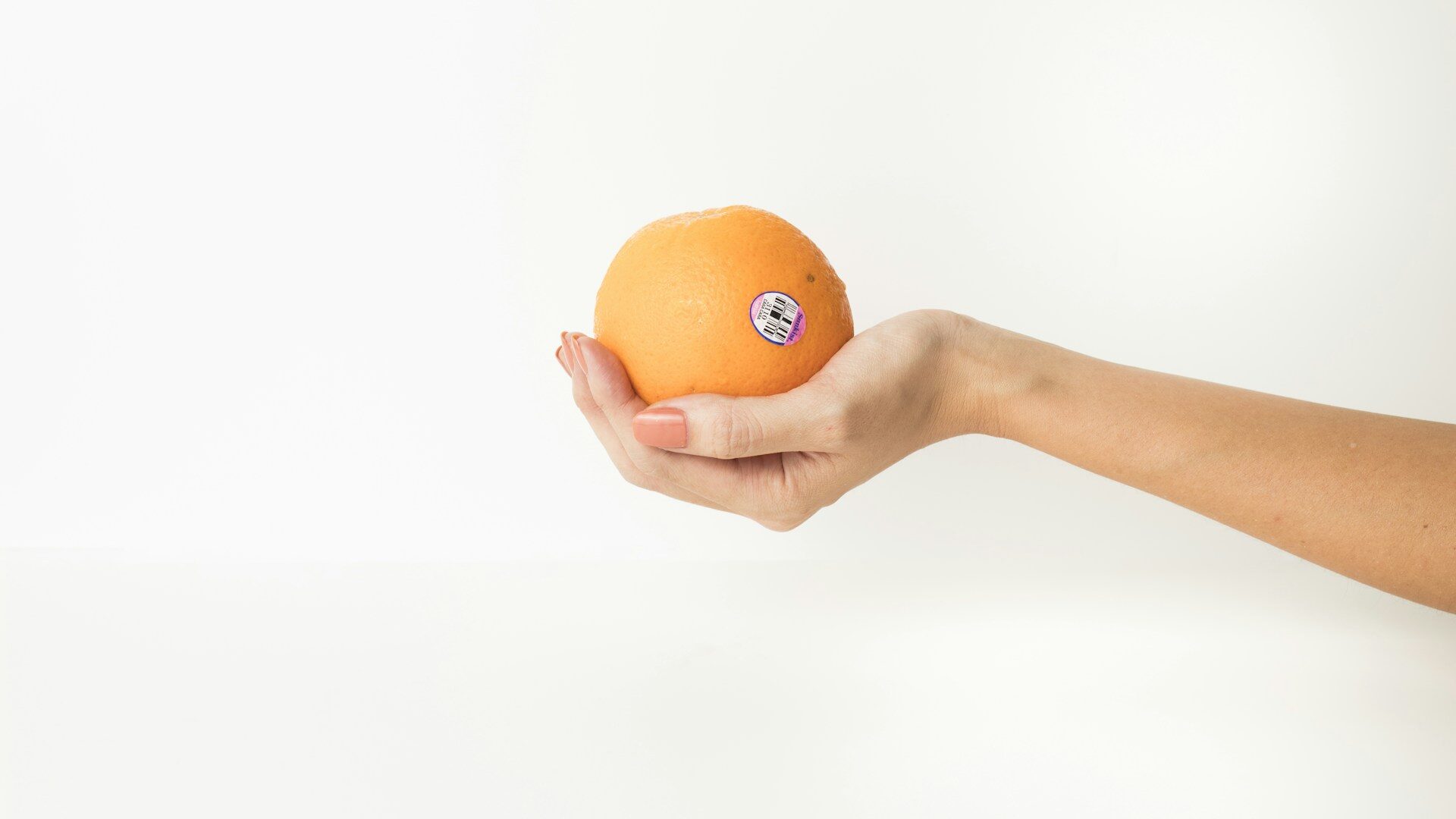 hand holding an orange massage ball against a white backgrou Hand holding an orange massage ball against a white background