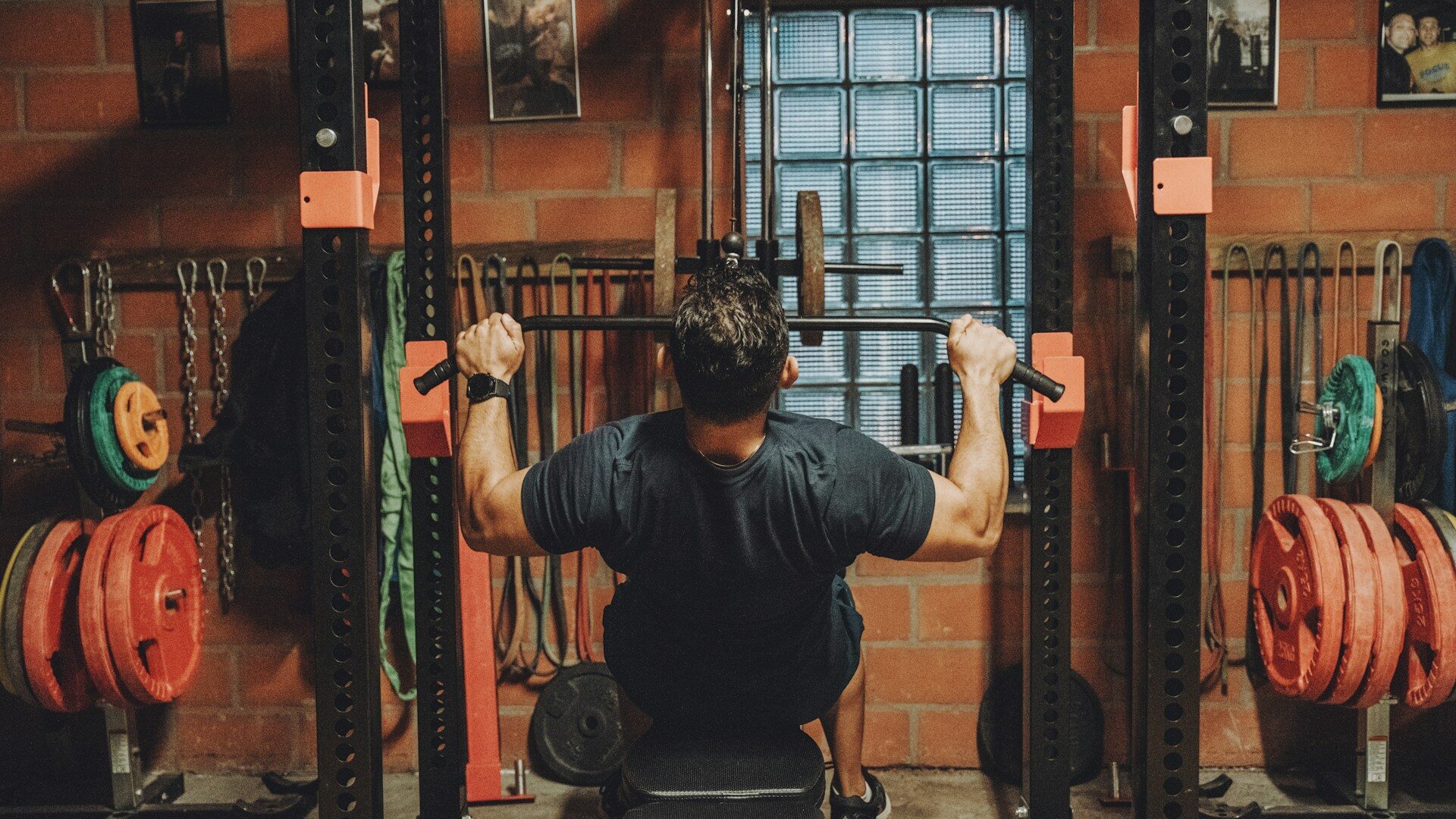 Lifter pressing inside a power rack with weight plates stored on the uprights