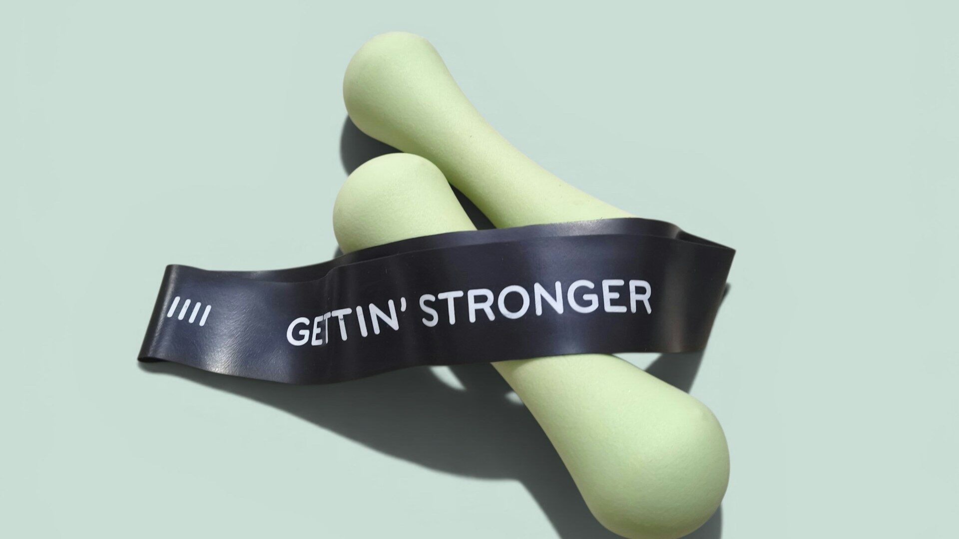 Light green dumbbells with a resistance band on a pastel background