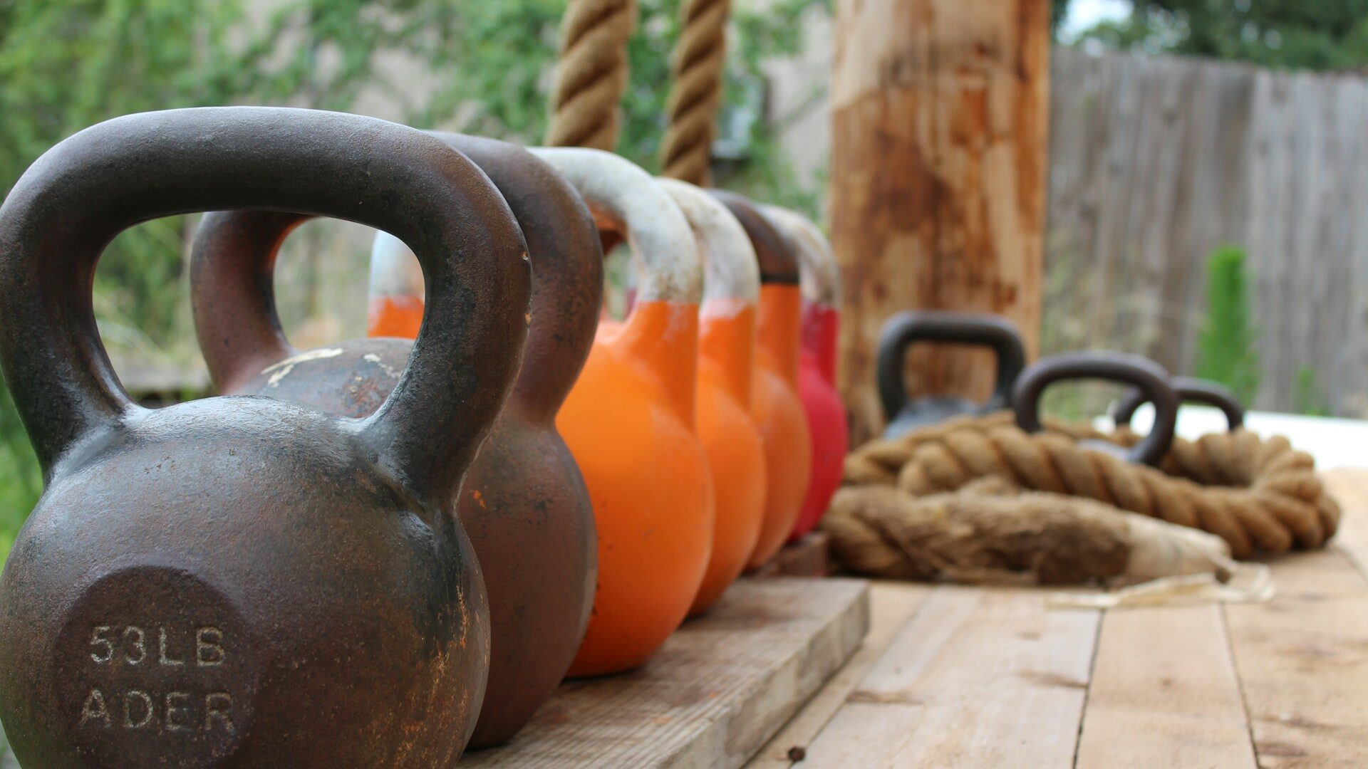 orange and iron kettlebells on a wooden platform Orange and iron kettlebells on a wooden platform