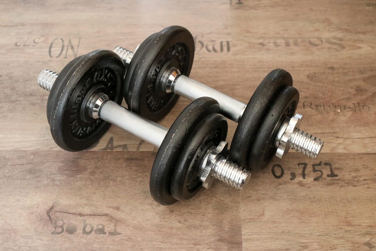 Pair of plate-loaded adjustable dumbbells with spin-lock collars on a wooden floor