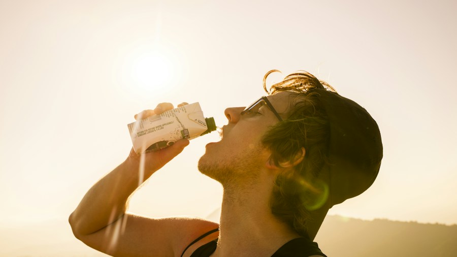 person drinking water from a bottle while exercising indoors Person drinking water from a bottle while exercising indoors