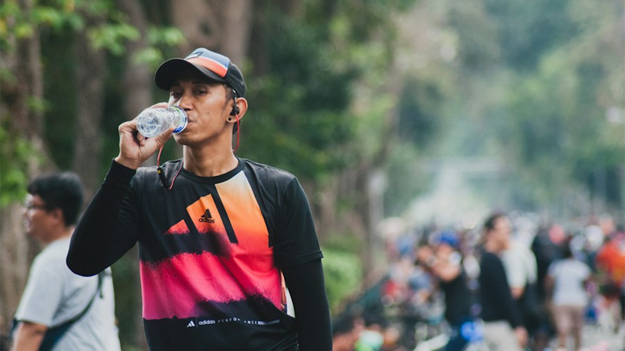 person drinking water from a bottle while exercising to stay Person drinking water from a bottle while exercising to stay hydrated during workout