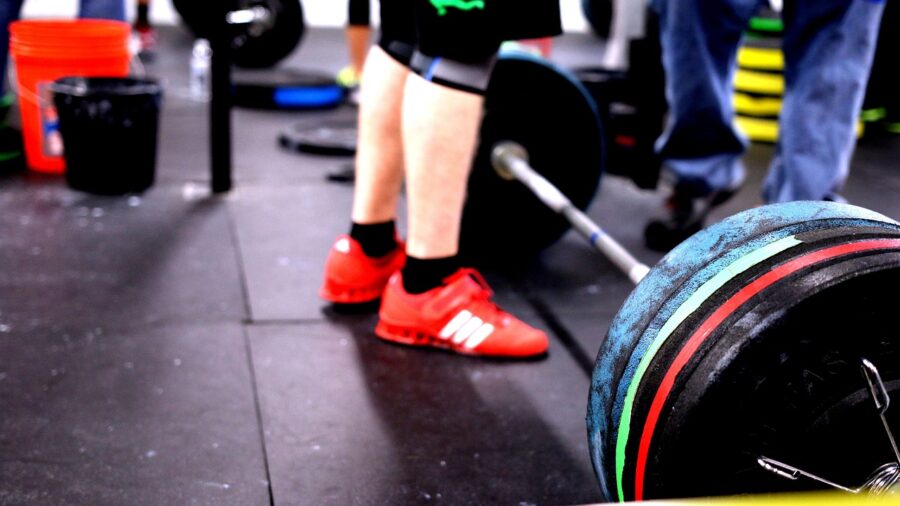 Person lifting a barbell in a home gym setting with proper form and technique