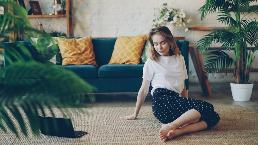 Person performing a hamstring stretch on a living room floor during a home workout session