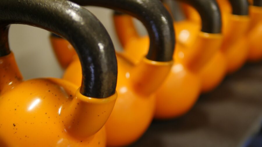 Person performing kettlebell swing exercise with cast iron kettlebell in home gym