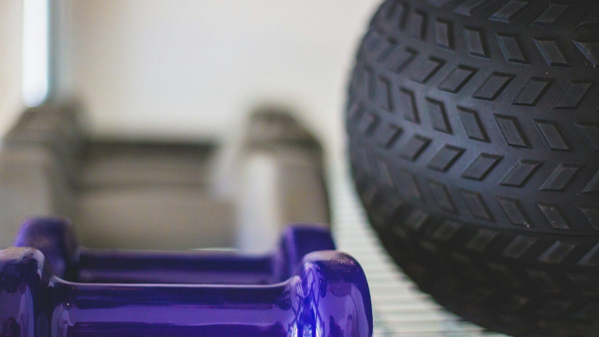 purple dumbbells next to a medicine ball on a light shelf Purple dumbbells next to a medicine ball on a light shelf
