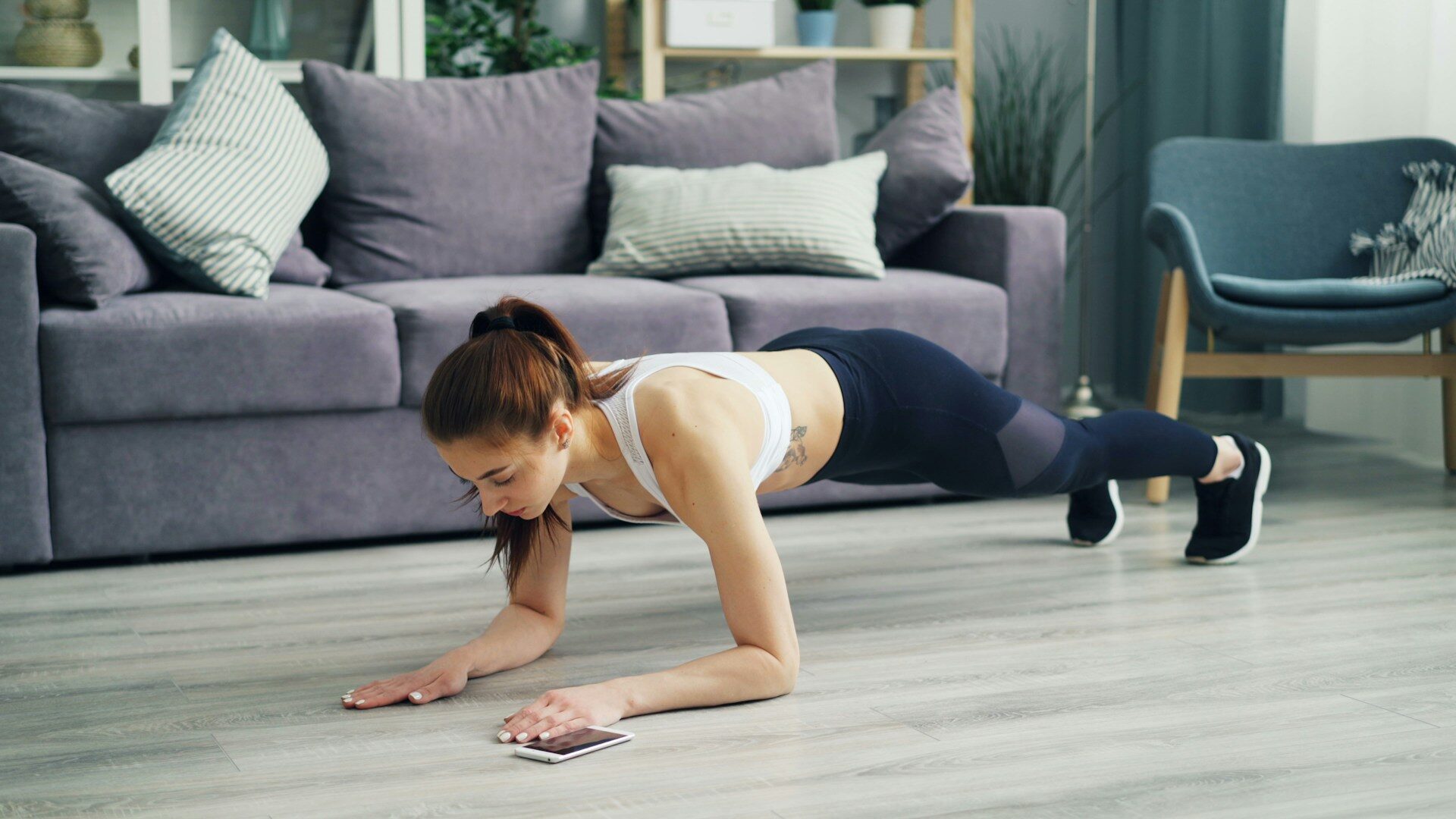 woman holding a plank on the floor of a small apartment livi Woman holding a plank on the floor of a small apartment living room