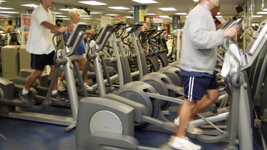 Woman using an elliptical machine for low-impact cardio exercise in a home gym setting
